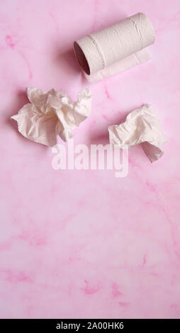 Bianco tessuto spiegazzato carta e carta igienica rotolo su un marmo rosa sfondo. Foto Stock