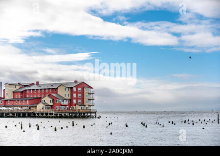 Rosso di edificio di legno sul vecchio molo pesca con pali di legno sporgente dall'acqua a bocca larga del fiume Columbia in Astoria city sulla Pacif Foto Stock