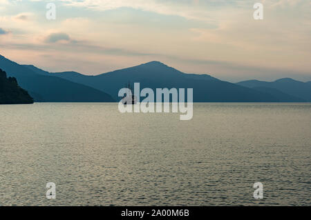 Lago di montagna nella nebbia al tramonto con la vecchia nave pirata cruising le acque. Lago Ashi, Hakone, Giappone Foto Stock