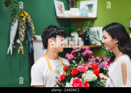 Giovani asiatici fioraio maschio hanno la conversazione con il cliente in negozio Foto Stock