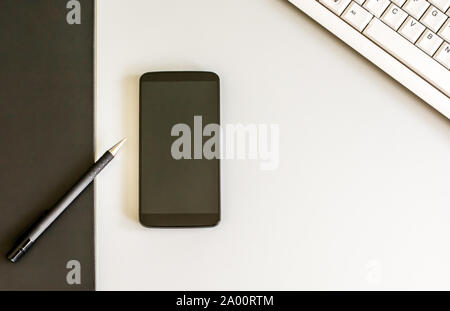 Escursioni con lo smartphone, la penna e la tastiera del computer visto da sopra Foto Stock