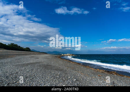 Spiaggia, coste di Shizouka con le montagne sullo sfondo. Spiaggia rocciosa con sabbia nera vulcanica, ciottoli e acque blu della Baia di Suruga, Pacific coa Foto Stock