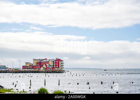 Rosso di edificio di legno sul vecchio molo pesca con pali di legno sporgente dall'acqua a bocca larga del fiume Columbia in Astoria city sulla Pacif Foto Stock