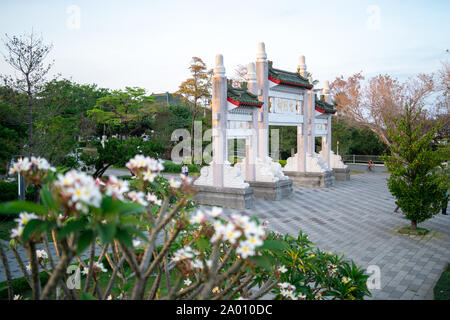 Kaohsiung, Taiwan: cancello di ingresso al Santuario dei Martiri di Kaohsiung a Shou Shan (Monkey mountain) con fiori di colore bianco nella parte anteriore Foto Stock