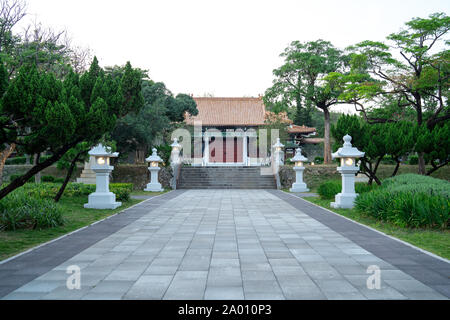 Kaohsiung: Il percorso che porta all'ingresso del Santuario dei Martiri Memorial Building con alberi verdi su entrambi i lati e cinese tradizionale luci da giardino Foto Stock