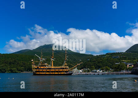 Hakone, Giappone - 3 Settembre 2016: imbarcazione turistica sul molo sul lago Ashi con sponde di Hakone e foresta montagne sullo sfondo Foto Stock