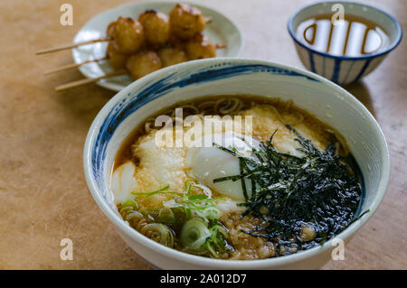 In tradizionale stile giapponese ramen, soba noodle soup con polpette di riso su un bastone e il tè verde sullo sfondo Foto Stock