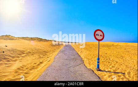 Incrinato strada asfaltata attraversando un arido terreno di dune con un sorpasso non firmare. Foto Stock