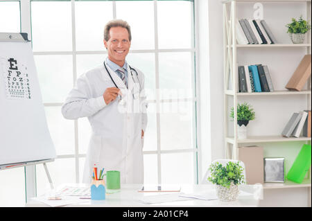 Medico senior presso il suo ufficio in ospedale positivo lavoro Foto Stock