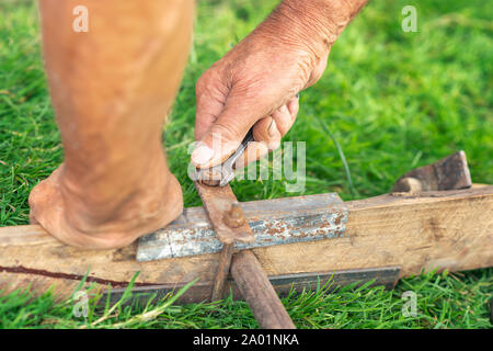 Le mani di un uomo anziano torcere il dado con una chiave sull'erba verde Foto Stock