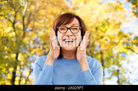 Senior donna in bicchieri chiamando oltre l'autunno park Foto Stock