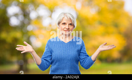 Senior donna scrollare nell'autunno park Foto Stock