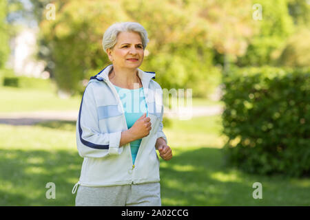 Senior donna che corre lungo il parco di estate Foto Stock