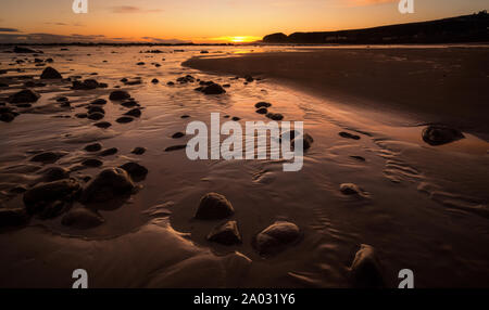 Inverno sunrise a Stonehaven sull'Aberdeenshire costa della Scozia. Il cielo si riflette nell'acqua sulla spiaggia. Foto Stock