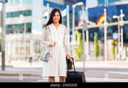 Felice giovane donna asiatica con borsa da viaggio in città Foto Stock