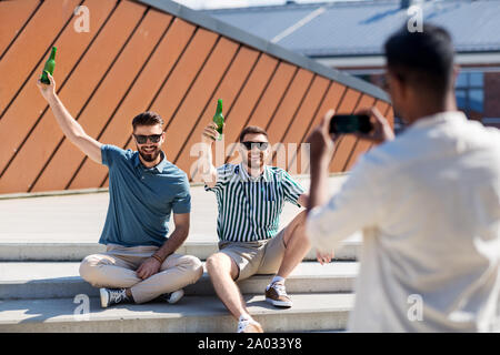 Uomo di fotografare gli amici a bere una birra su strada Foto Stock