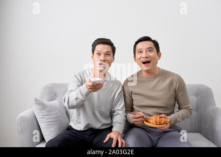 Gli uomini seduti sul divano guardando film in televisione insieme a casa. Foto Stock