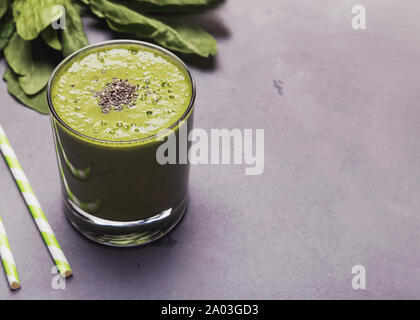 Frullato verde cosparso di chia semi sul colore grigio tableclose-up Foto Stock