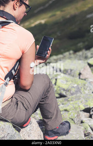 La vita attiva di diabetici, donna seduta guardando il telefono cellulare con la verifica del livello di glucosio dalla nuova tecnologia del sensore remoto montato sulla sua mano Foto Stock