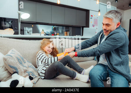 Follow us. Tipo uomo seduto vicino a sua figlia e prendendo il suo gadget indietro Foto Stock