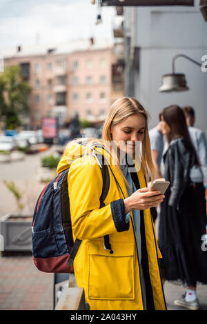 Donna che cammina e utilizzando uno smartphone in strada Foto Stock