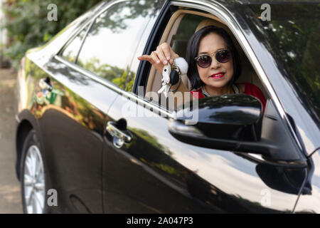 Felice senior donna alla guida e mostrando la sua nuova chiave auto. Foto Stock