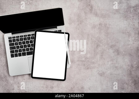 Aprire il portatile con tavoletta digitale e matita bianca sul cemento grigio Sfondo. Tavoletta digitale con schermo bianco. Vista da sopra con copia spazio per il testo. Fla Foto Stock