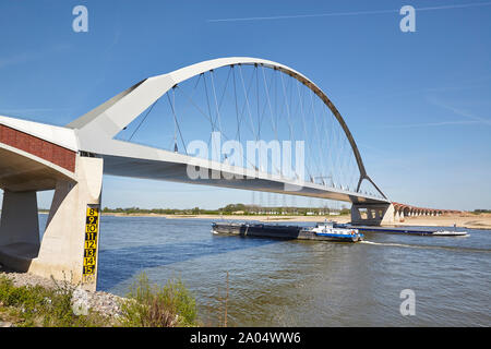 River Barge navigazione sotto un ponte denominato De Oversteek che attraversa il fiume Waal a Nijmegen nei Paesi Bassi Foto Stock