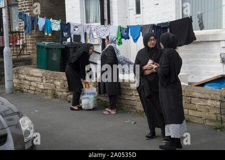 Donna musulmana Regno Unito. Bradford Yorkshire 2019, 2010 Donne che chiacchierano per strada indossando abiti neri tradizionali chiamati Abaya. Questo è indossato in pubblico. Lavare appeso su una linea di vestiti nel giardino anteriore. HOMER SYKES Foto Stock