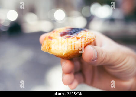 Tradizionale dolce portoghese in mano d'uomo. Pastel de nata. Foto Stock