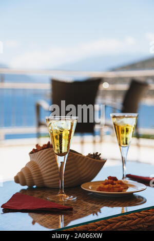 Due bicchieri a freddo di tè freddo, vino bianco con cubetti di ghiaccio e un greco tradizionale snack con un greco Fava su un tavolo in un hotel resort. Foto Stock