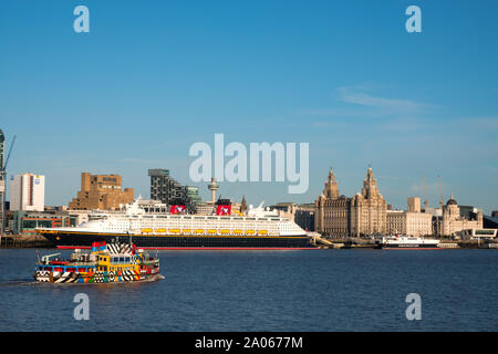 Il Mersey Ferry passa la nave da crociera Disney Magic dopo che esso chiama in Liverpool cruise terminal di fronte al magnifico litorale edifici. Foto Stock