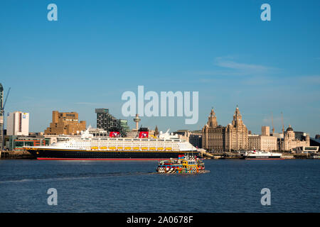 Il Mersey Ferry passa la nave da crociera Disney Magic dopo che esso chiama in Liverpool cruise terminal di fronte al magnifico litorale edifici. Foto Stock