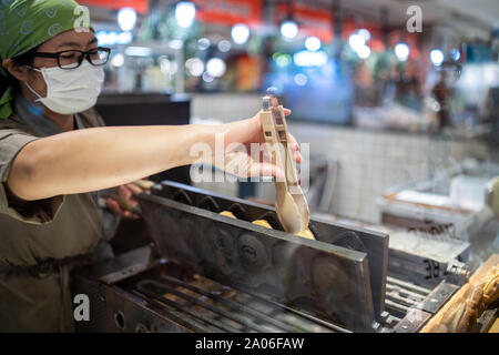 Kaohsiung, Taiwan: tradizionali taiwanesi / giapponese di cialde. Femmina lavoratore asiatico preparando a forma di pesce waffle appena sfornato in un hot Foto Stock