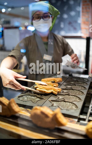 Kaohsiung, Taiwan : tradizionali taiwanesi / giapponese di cialde. Femmina lavoratore asiatico preparando a forma di pesce waffle appena sfornato in un hot Foto Stock