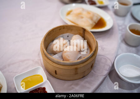 Stile di Hong Kong di gamberi cotti al vapore gnocchi in un bambù il cestino per la cottura a vapore su un ristorante tabella Foto Stock