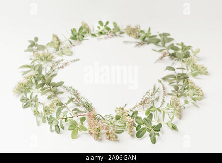 Bella gara e corona telaio con fiori di colore rosa, Heath, rami e foglie su sfondo bianco. Vista dall'alto. Copia dello spazio. Foto Stock