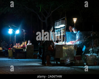 Kaohsiung, Taiwan: due uomini sono sellung fatto a mano glas arte e gioielli a due donne a street negozio in un parco di notte Foto Stock