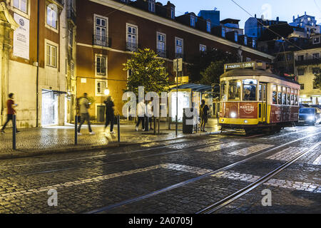 Lisbona, Portogallo - agosto, 2019: giallo tram turistico di notte su una strada a ciottoli nel punto di vista del Portas do Sol al quartiere di Alfama Foto Stock