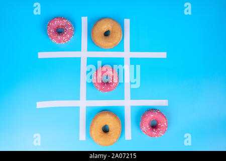 Immagine concettuale, tre in una fila di ciambelle smaltata su sfondo blu. Visto da sopra Foto Stock