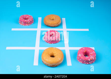 Immagine concettuale, tre in una fila di ciambelle smaltata su sfondo blu. Primo piano Foto Stock