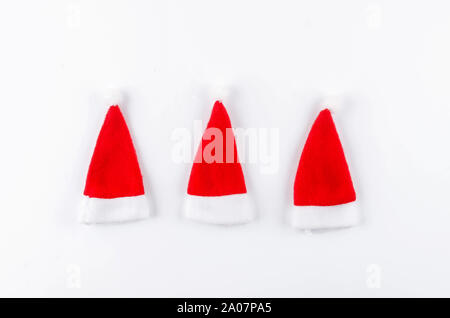 Natale o Capodanno sfondo. Molti cappelli di Babbo Natale su sfondo bianco. Vacanze di Natale concetto. Appartamento laico, vista dall'alto, spazio di copia Foto Stock