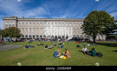 Studenti e rilassante ejoying una piacevole giornata con bel tempo sul prato al di fuori del Libro di Kells, Trinità vecchia libreria a Dublino, Irlanda. Foto Stock