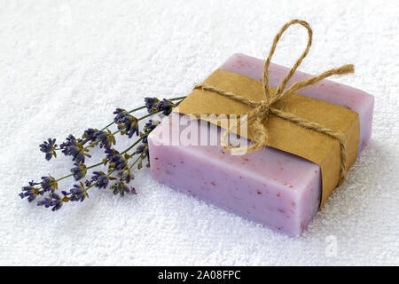 Saponetta a secco con aromatico fiori di lavanda. Viola saponi fatti a mano su un bianco in spugna di cotone asciugamano. Articoli da bagno naturali e prodotti di igiene con erbe aromatiche Foto Stock