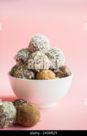 Prodotti naturali fatti in casa le sfere di energia, vegan tartufo al cioccolato con cacao, noci di cocco su sfondo rosa. Spazio per il testo. Cibo sano per i bambini e i dolci subst Foto Stock