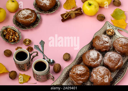 Muffin fatti in casa con le mele e i dadi e due tazze di caffè disposti su un sfondo rosa, vista dall'alto, copia dello spazio, composizione autunnale, orizzontale Foto Stock