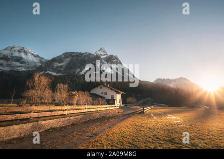 Alpi innevate cime delle montagne e la fattoria austriaca nella luce della sera, in una giornata di sole invernale, in Ehrwald, Austria. Dicembre tramonto paesaggio. Foto Stock