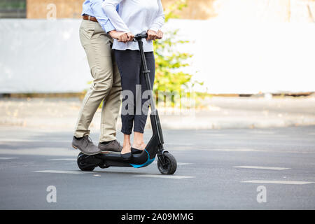 Ritratto di coppia felice a cavallo su scooter elettrico sulla strada in città Foto Stock