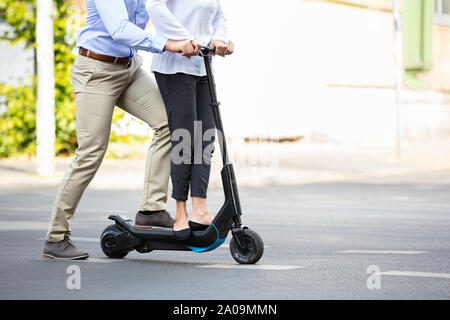 Ritratto di coppia felice a cavallo su scooter elettrico sulla strada in città Foto Stock