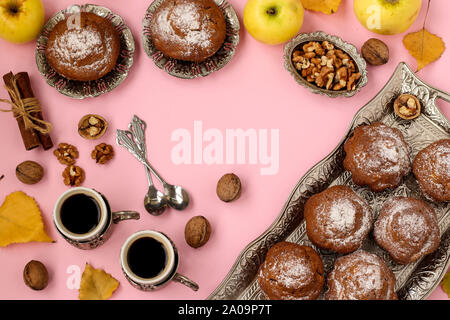 Muffin fatti in casa con le mele e i dadi e due tazze di caffè disposti su un sfondo rosa, vista dall'alto, copia dello spazio, composizione autunnale, orizzontale Foto Stock